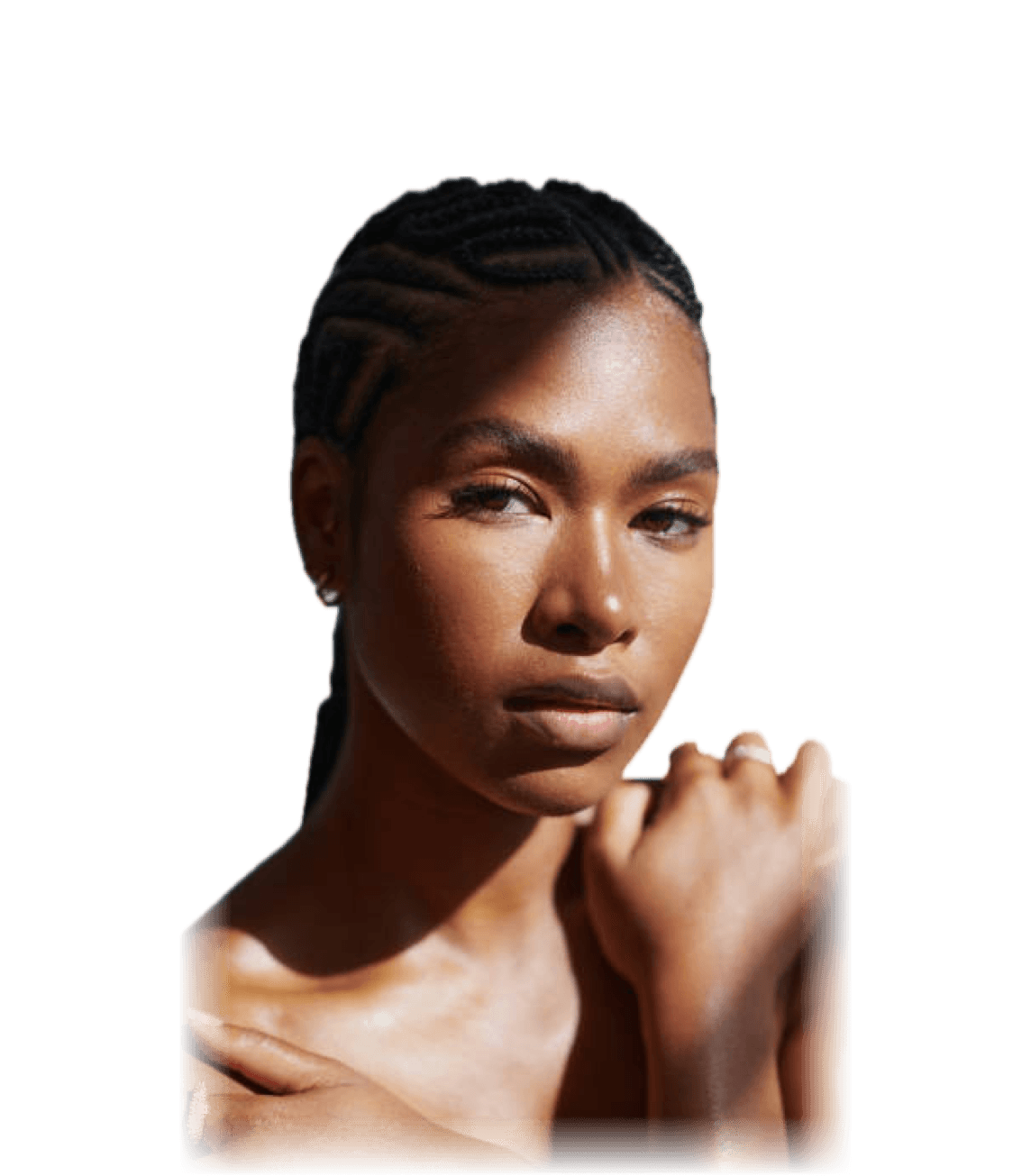 Woman with cornrow braids in soft sunlight, hands resting on her shoulders